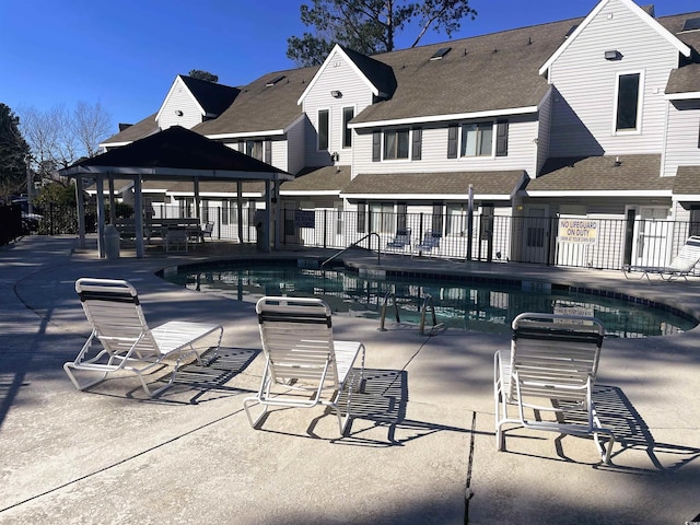 rear view of property featuring a community pool, a gazebo, and a patio area