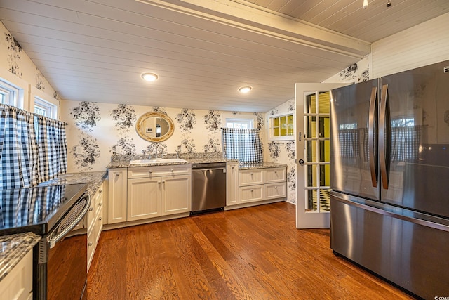 kitchen with light stone countertops, dark hardwood / wood-style floors, white cabinets, appliances with stainless steel finishes, and sink