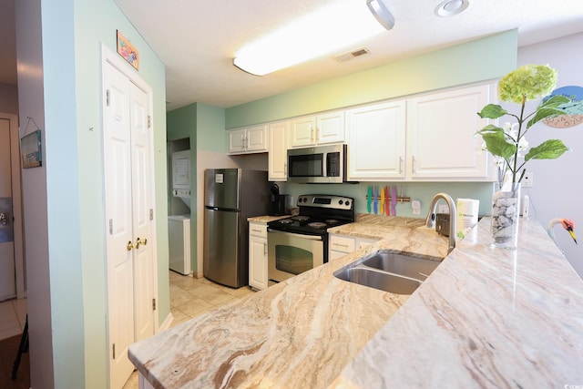 kitchen with light stone countertops, sink, light tile patterned flooring, white cabinets, and appliances with stainless steel finishes