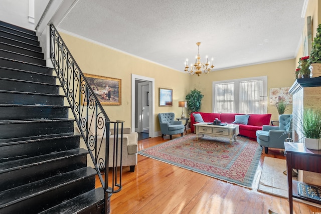 living room featuring a chandelier, hardwood / wood-style floors, a textured ceiling, and crown molding