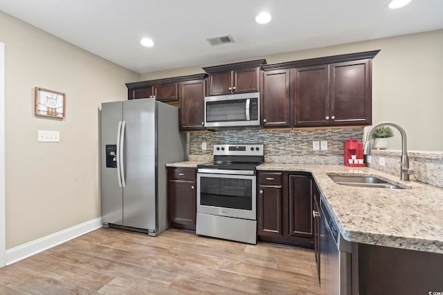 kitchen with sink, light hardwood / wood-style flooring, backsplash, dark brown cabinets, and stainless steel appliances