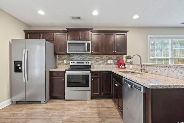 kitchen featuring sink, backsplash, light wood-type flooring, and appliances with stainless steel finishes