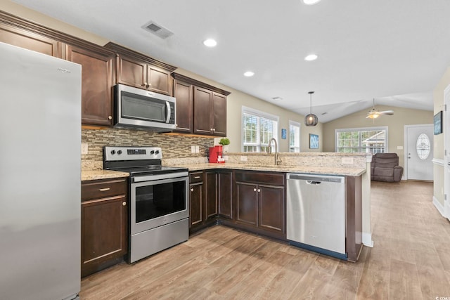 kitchen featuring sink, appliances with stainless steel finishes, decorative light fixtures, vaulted ceiling, and kitchen peninsula