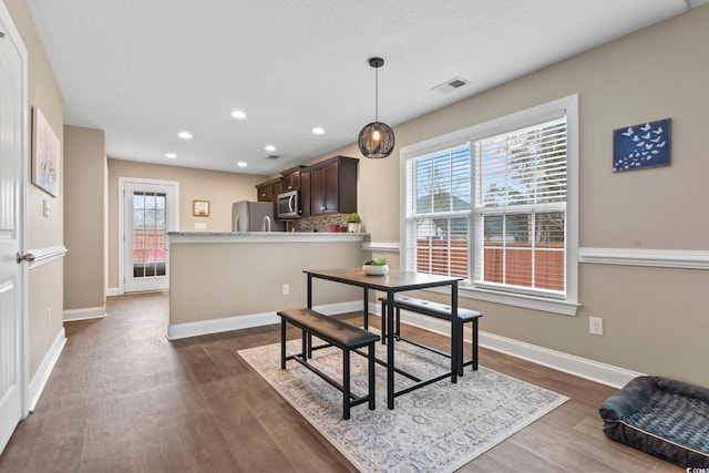 dining space with dark wood-type flooring, a healthy amount of sunlight, and a textured ceiling