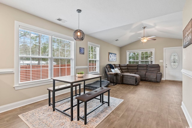 dining area with vaulted ceiling, ceiling fan, a textured ceiling, and light hardwood / wood-style floors