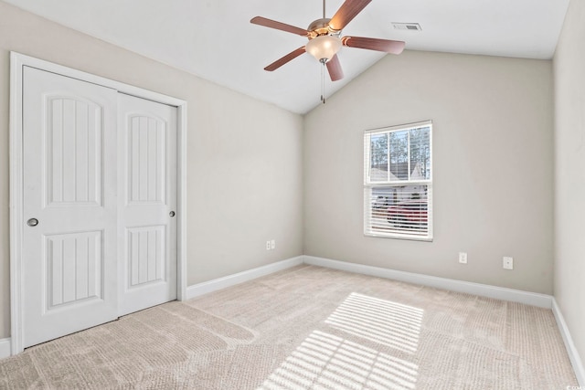 unfurnished bedroom with ceiling fan, light colored carpet, lofted ceiling, and a closet