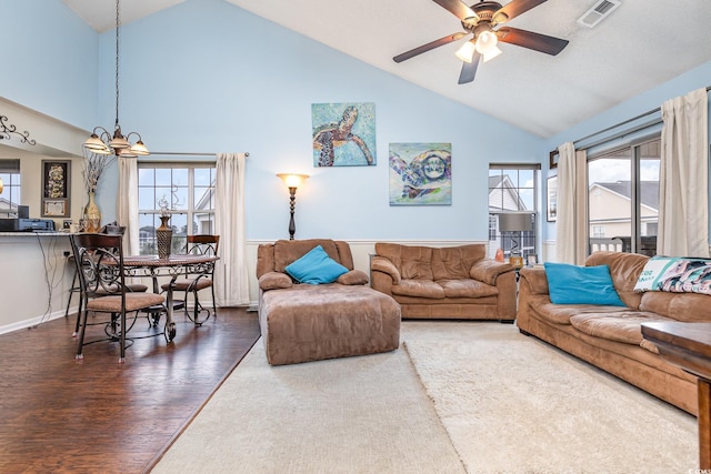 living room featuring ceiling fan with notable chandelier, dark hardwood / wood-style floors, and vaulted ceiling