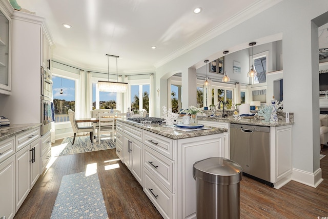 kitchen featuring kitchen peninsula, stainless steel appliances, decorative light fixtures, a center island, and white cabinetry