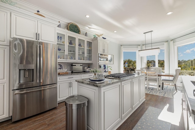 kitchen with stainless steel appliances, a kitchen island, crown molding, pendant lighting, and white cabinets