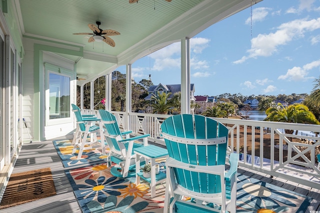 wooden terrace with ceiling fan, a water view, and covered porch