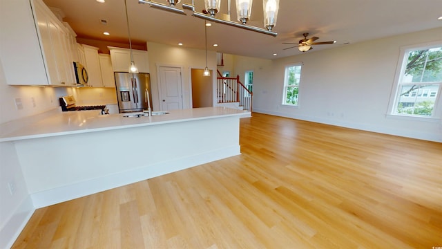 48 Furman Ln, Pawleys Island, SC 29585 - kitchen with stainless steel fridge, gas stove, a peninsula, light wood-type flooring, and light countertops