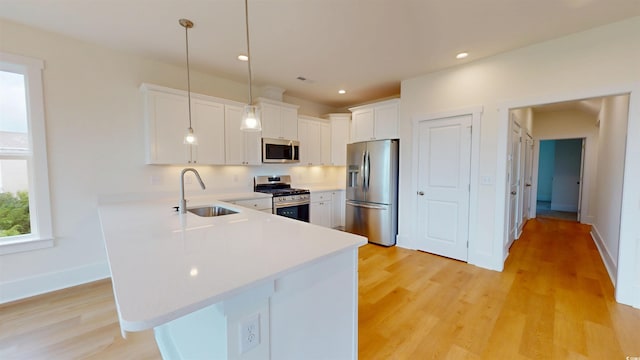 48 Furman Ln, Pawleys Island, SC 29585 - kitchen with stainless steel appliances, light countertops, a peninsula, light wood finished floors, and white cabinets