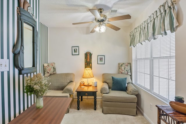 sitting room featuring light carpet, a textured ceiling, and ceiling fan