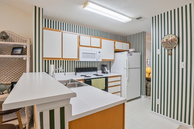 kitchen featuring a breakfast bar, a textured ceiling, white appliances, sink, and white cabinets