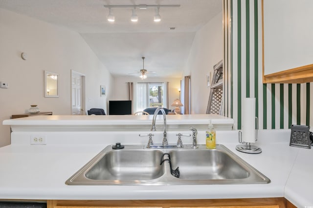 kitchen with a textured ceiling, ceiling fan, sink, and vaulted ceiling