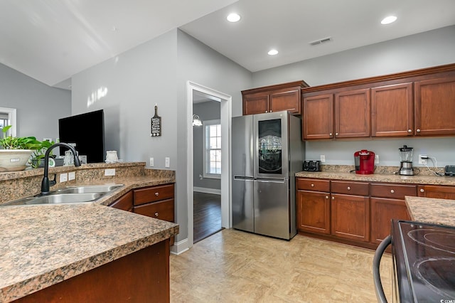 kitchen featuring stainless steel fridge, stove, lofted ceiling, and sink