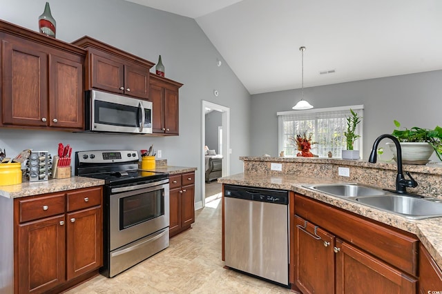 kitchen featuring lofted ceiling, sink, appliances with stainless steel finishes, decorative light fixtures, and light stone counters