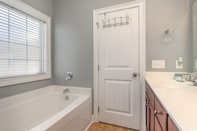 bathroom with tile patterned flooring, plenty of natural light, a bathtub, and vanity