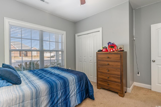 bedroom featuring light colored carpet, a closet, and ceiling fan