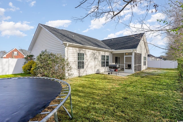 back of house with a yard, a patio, a trampoline, and a sunroom