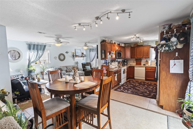 tiled dining area with ceiling fan, a healthy amount of sunlight, and a textured ceiling