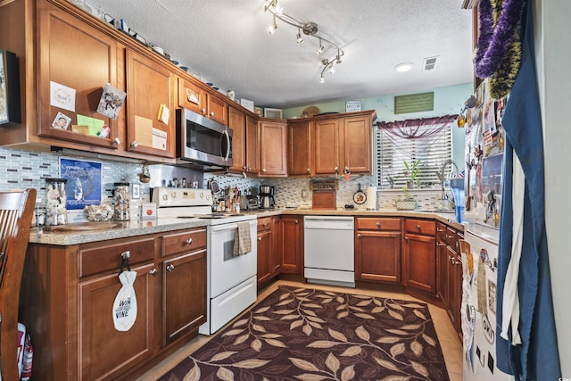 kitchen with tile patterned flooring, white appliances, a textured ceiling, and tasteful backsplash