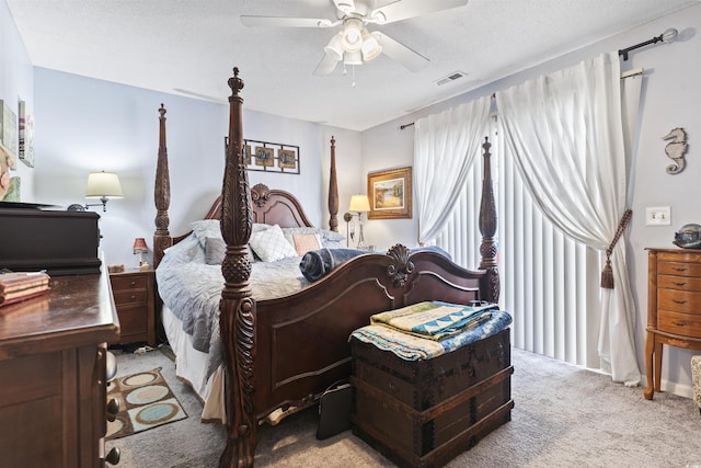 carpeted bedroom featuring ceiling fan and a textured ceiling