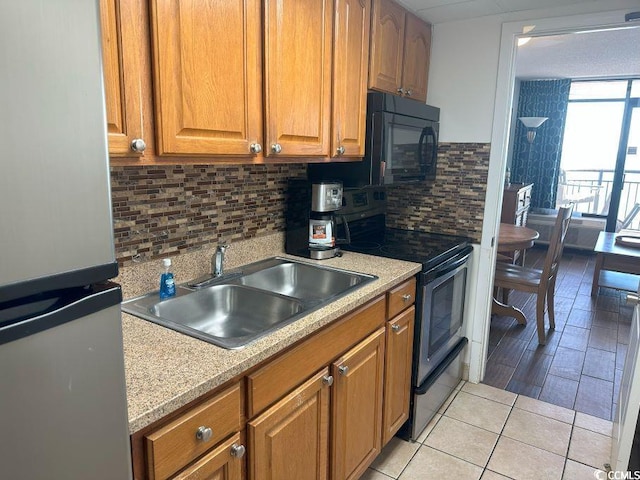 kitchen with backsplash, sink, light tile patterned floors, and stainless steel appliances