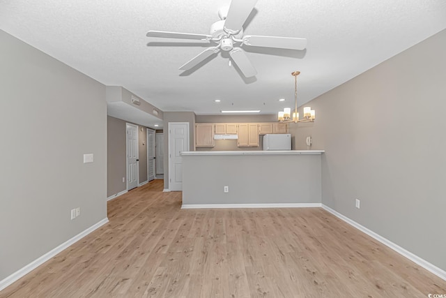 interior space featuring light brown cabinets, white fridge, light hardwood / wood-style floors, and a textured ceiling