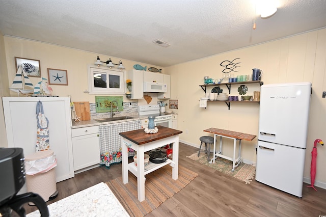 kitchen featuring white appliances, sink, a textured ceiling, and white cabinets