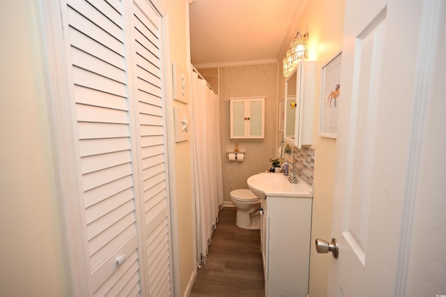 bathroom featuring wood-type flooring, decorative backsplash, vanity, toilet, and crown molding