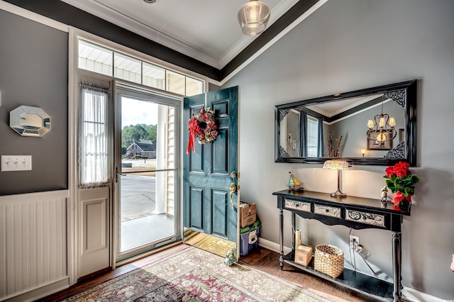 foyer entrance with radiator heating unit, a notable chandelier, ornamental molding, and hardwood / wood-style floors