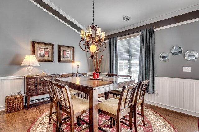 dining area featuring crown molding, hardwood / wood-style floors, vaulted ceiling, and a notable chandelier