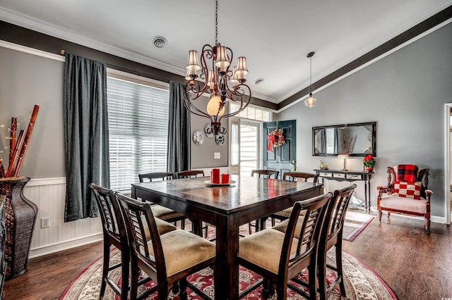 dining area featuring dark wood-type flooring, vaulted ceiling, crown molding, and an inviting chandelier