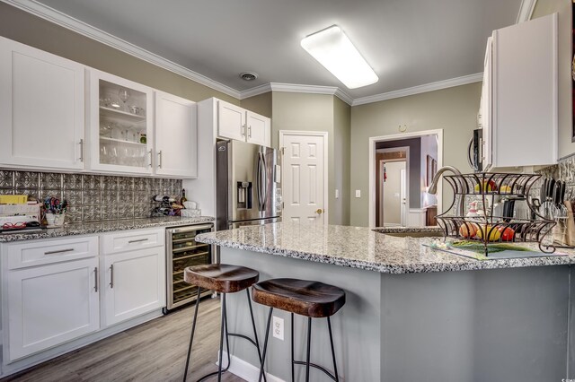 kitchen featuring a kitchen bar, white cabinetry, stainless steel appliances, and wine cooler