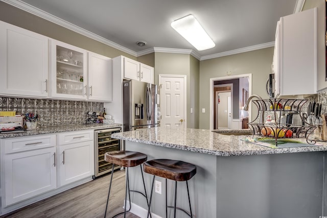 kitchen with appliances with stainless steel finishes, white cabinets, beverage cooler, and a kitchen breakfast bar