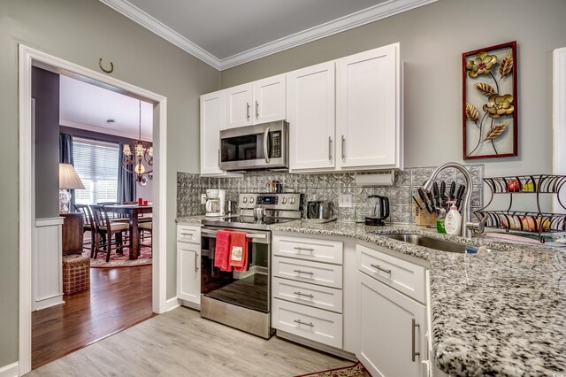 kitchen with white cabinets, crown molding, light wood-type flooring, light stone counters, and stainless steel appliances