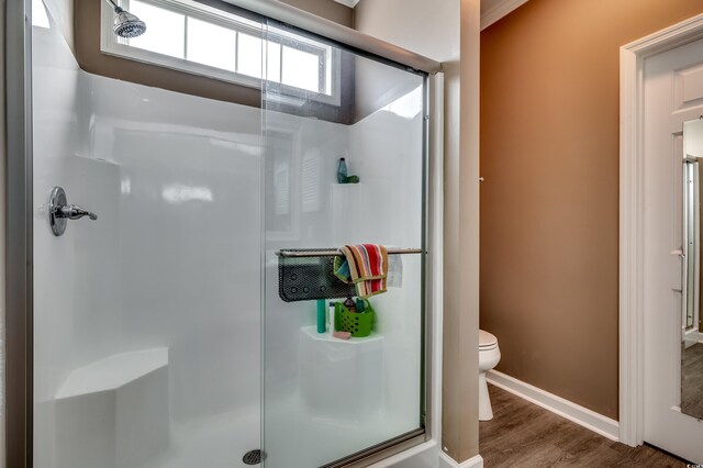 bathroom with a shower with door, hardwood / wood-style floors, and toilet