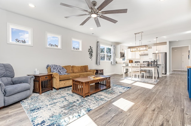 living room with light hardwood / wood-style flooring, ceiling fan, and a healthy amount of sunlight