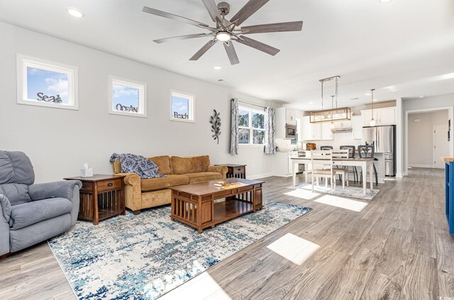 living room with light hardwood / wood-style flooring, ceiling fan, and a healthy amount of sunlight