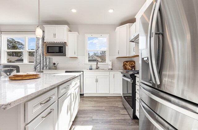 kitchen featuring appliances with stainless steel finishes, backsplash, white cabinetry, and pendant lighting