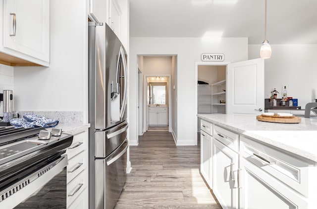 kitchen with white cabinets, stainless steel refrigerator with ice dispenser, light hardwood / wood-style flooring, decorative light fixtures, and light stone counters