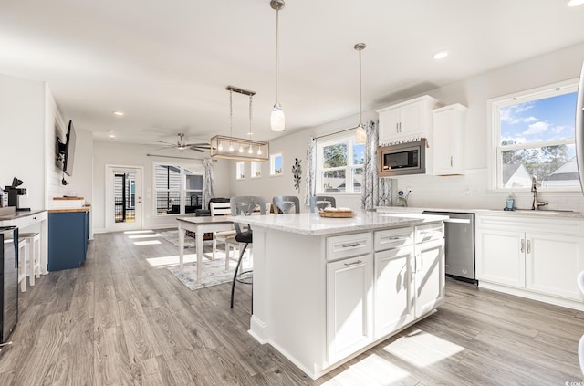 kitchen featuring ceiling fan, sink, a center island, white cabinets, and appliances with stainless steel finishes