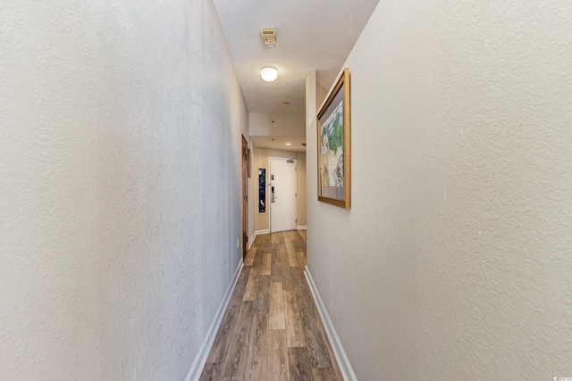 hallway with baseboards, dark wood-style flooring, and a textured wall