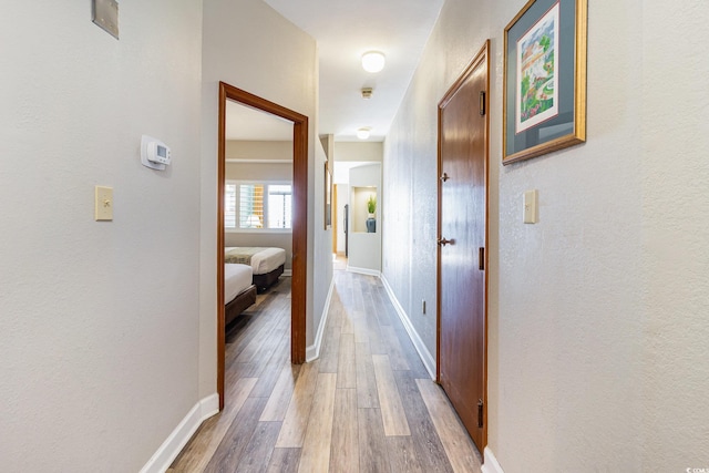 hallway featuring baseboards and wood finished floors