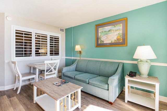 living room featuring visible vents, baseboards, and wood finished floors