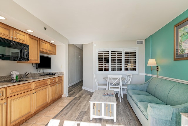 living room with light wood-type flooring, visible vents, baseboards, and recessed lighting