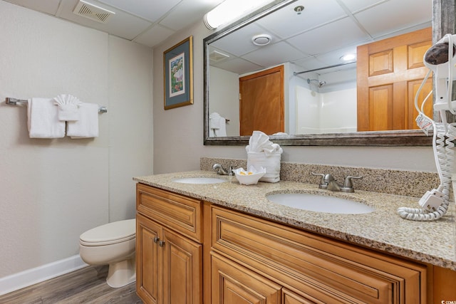 bathroom with visible vents, toilet, a paneled ceiling, and a sink