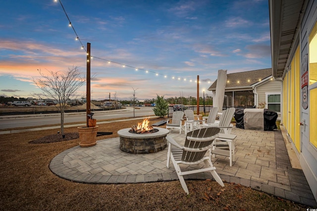 patio terrace at dusk featuring area for grilling and an outdoor fire pit