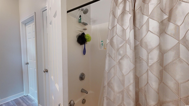 bathroom with shower / bathtub combination with curtain and wood-type flooring